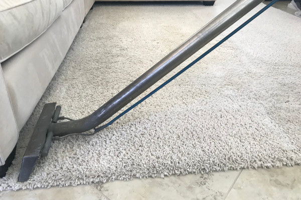 close up of a carpet cleaning wand being used on a white rug