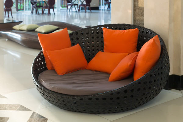 orange upholstered pillows on a black wicker couch