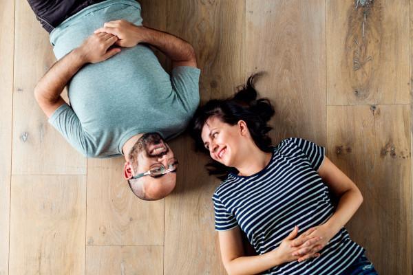 happy couple laying on a wooden floor