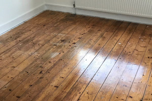 Freshly cleaned wooden floors showing reflection from nearby window