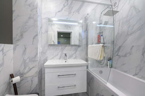 bathtub and counter next to marble walls