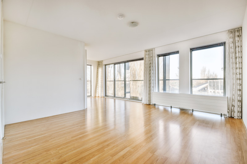 empty living room with clean wood effect laminate floors showing reflection from windows