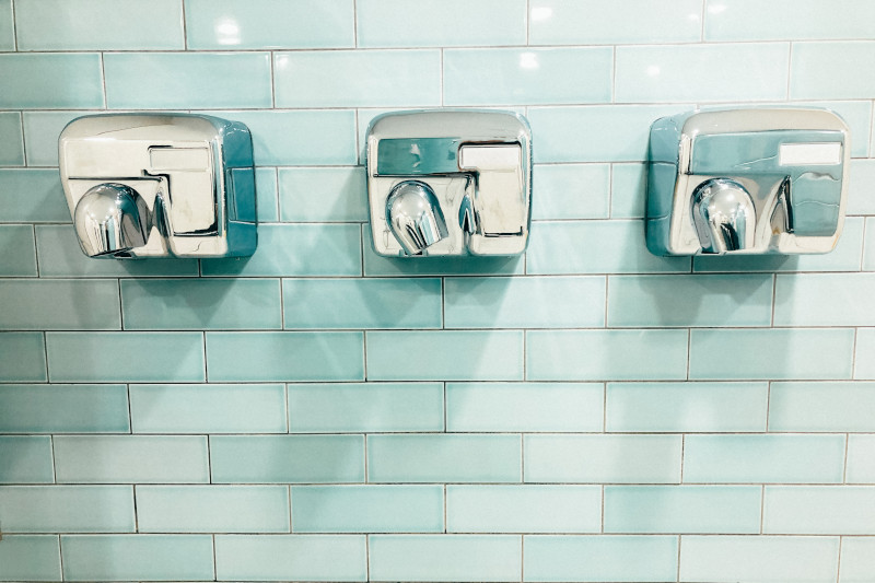 three air hand dryers hanging on a clean ceramic aqua-coloured wall tiles