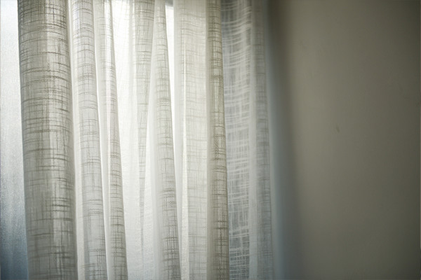 clean lace curtains hanging over a window with light shining through